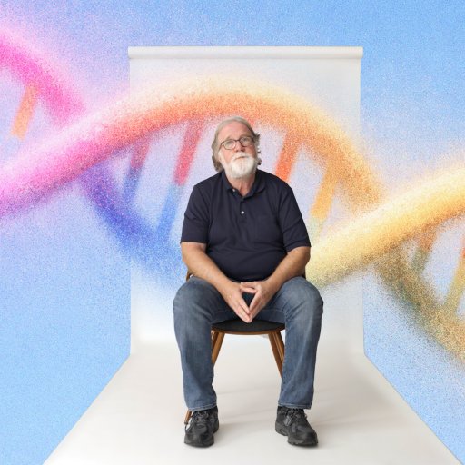 An older man with a white beard sits on a chair against a white backdrop, with a large, colorful DNA double helix illustration in the background.