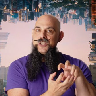 A bald man with a long beard and handlebar mustache gestures with his hands against a backdrop of an upside-down cityscape wearing a purple shirt.