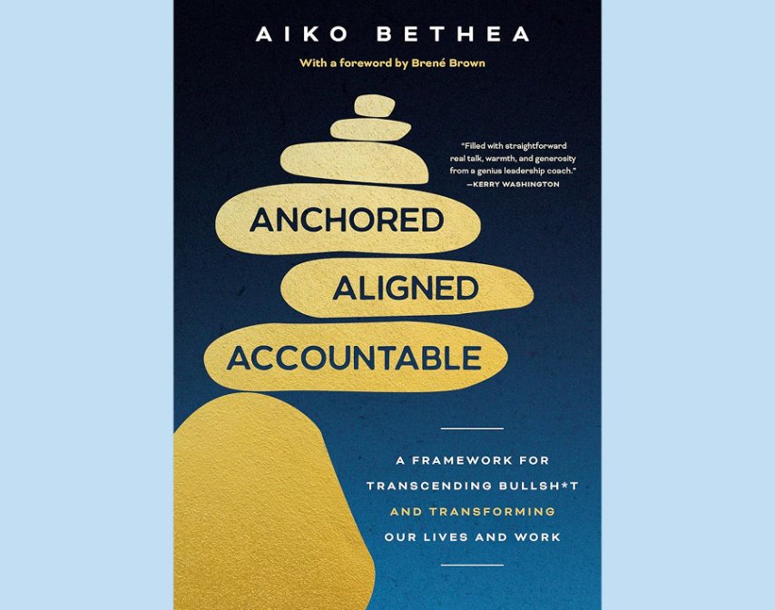 Book cover for "Anchored, Aligned, Accountable" by Aiko Bethea, featuring gold stacked stones on a blue background and a subtitle about transforming lives and work by overcoming the false urgency myth.