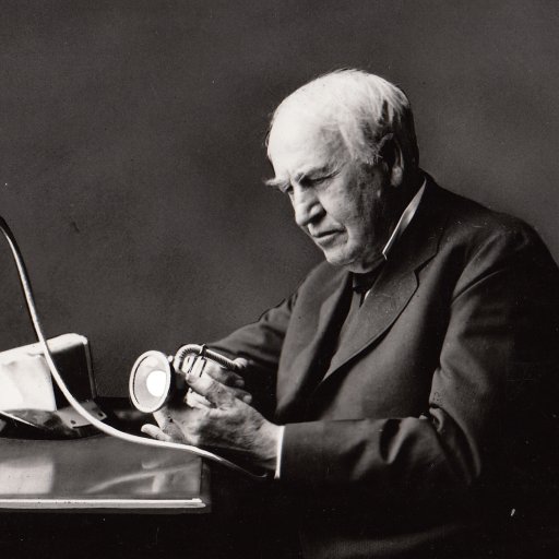 Elderly man examining a blood pressure monitor at a table.