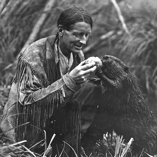 An outrageous man kneeling in the water with a beaver.