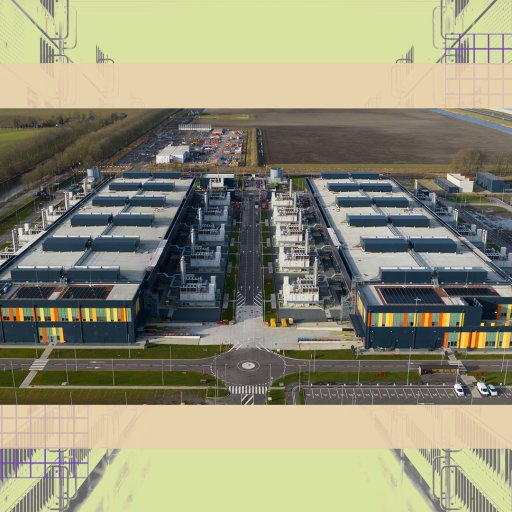 Aerial view of a large, modern data center complex with two main rectangular buildings separated by a central road, surrounded by fields and parking areas.