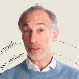 A middle-aged man with light hair and a beard, wearing a blue sweater over a white shirt, stands in front of a neutral background with faint, curved text elements.